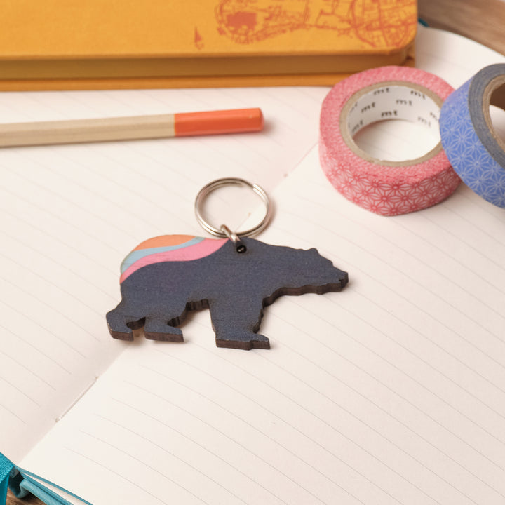 Unique Father’s Day present – customisable bear keyring on printed message card, surrounded by notebooks and tape.