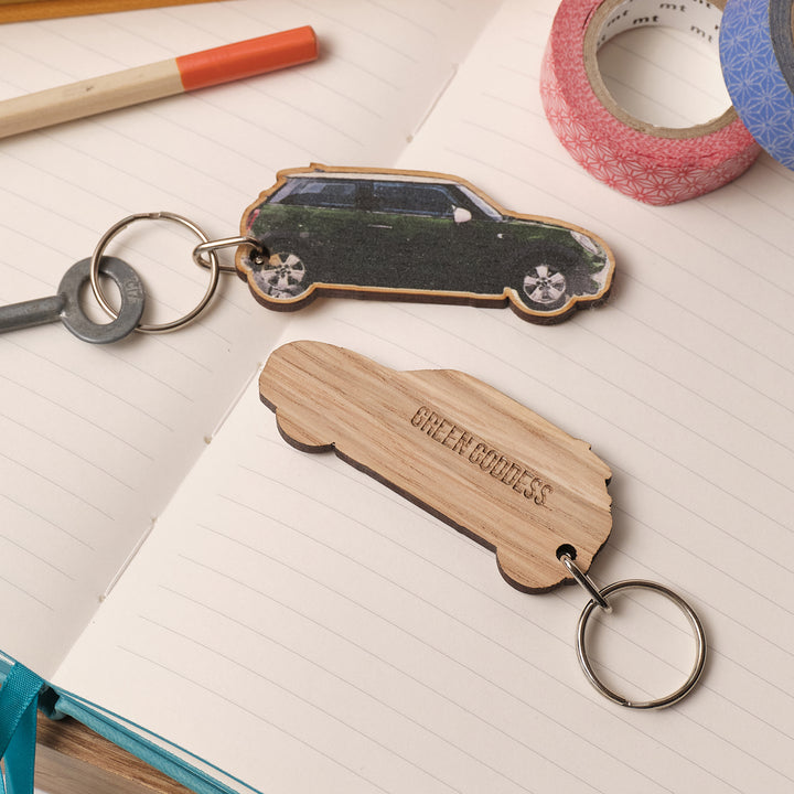 Wooden personalised printed in the UK keychain shaped like a car sat on a notebook with stationery items. Choose your own text, perfect unique travel gift for parents or new drivers.