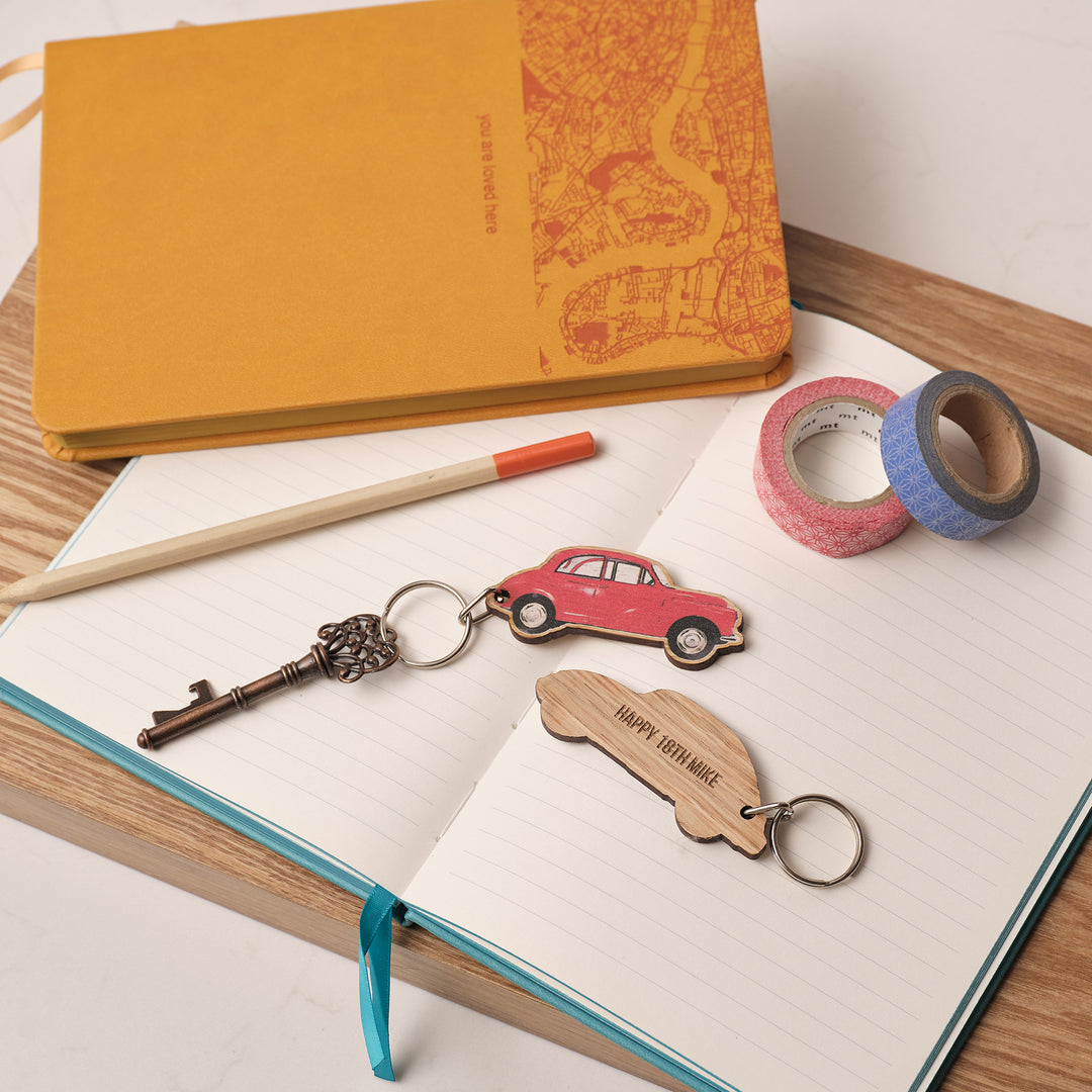 Morris Minor vintage car lovers keyring with a red car design, wooden keychain with personalised text, setup on an open notebook next to washi tape and a pencil. Perfect car accessory Birthday or Christmas gift for that motor lover in your life of for Dads for fathers day. Or treat your New Driver with a special place to put their keys.