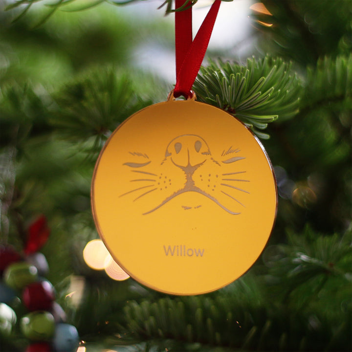 Gold medal-like personalised bauble Christmas tree decoration with space for your pets name to be engraved, strung on a red ribbon on a real Christmas tree. For your dogs 1st first Christmas or a gift for that number one pet lover in your life.