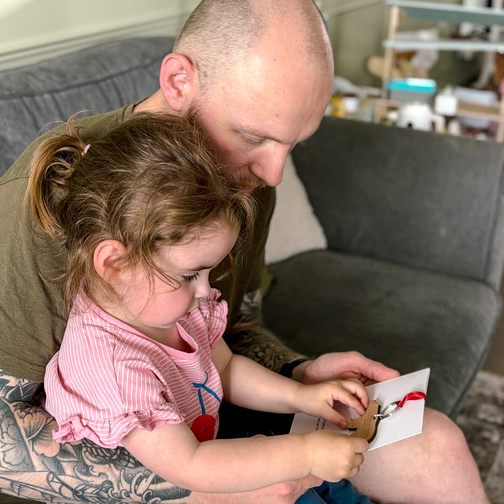 Unique Father’s Day present – customisable bear keyring on printed message card, young girl and dad holding card, reading message on the reverse