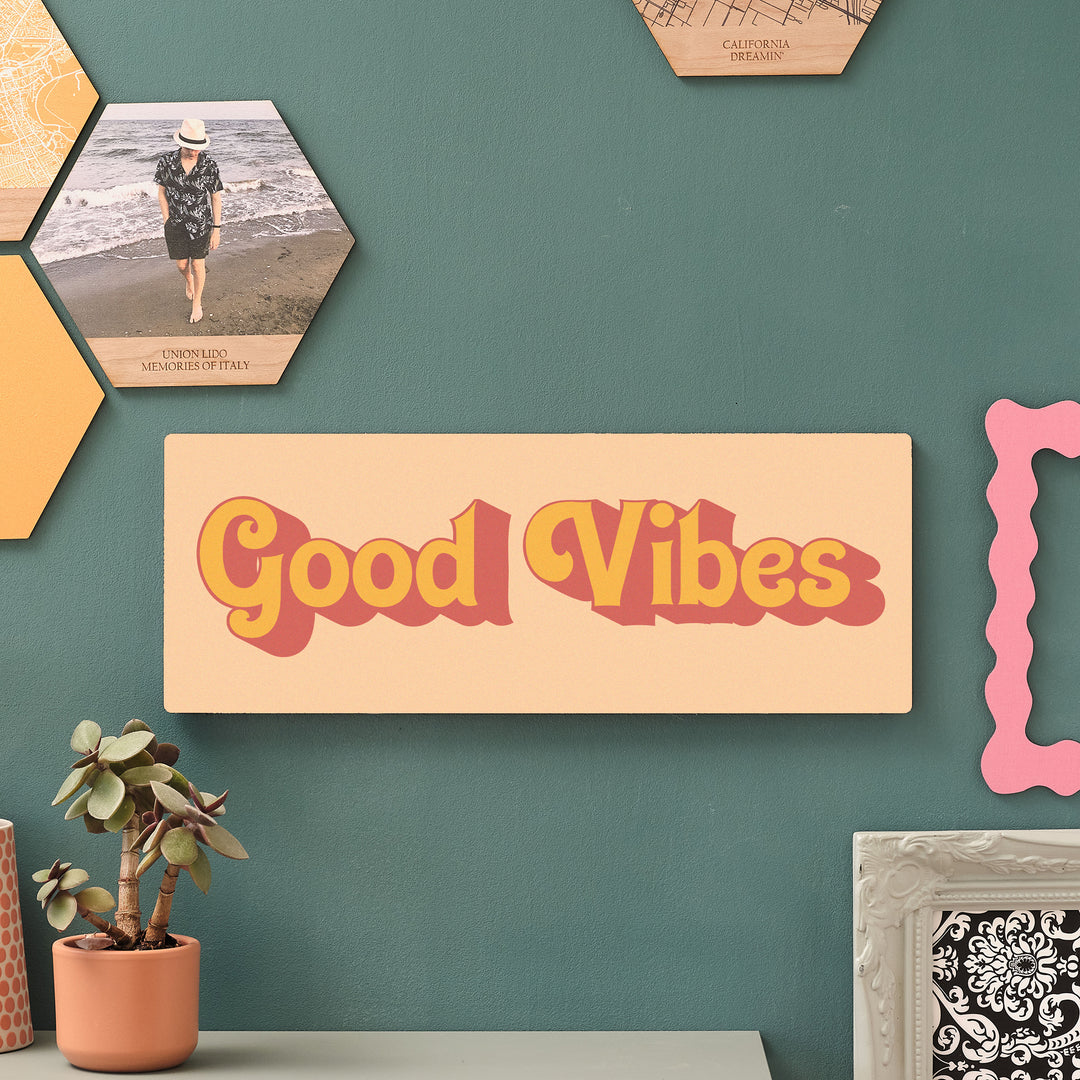Good Vibes wooden wall art in beachy yellows displayed on a green wall with indoor plants and hexagon decor – perfect for uplifting hallway or home office styling.