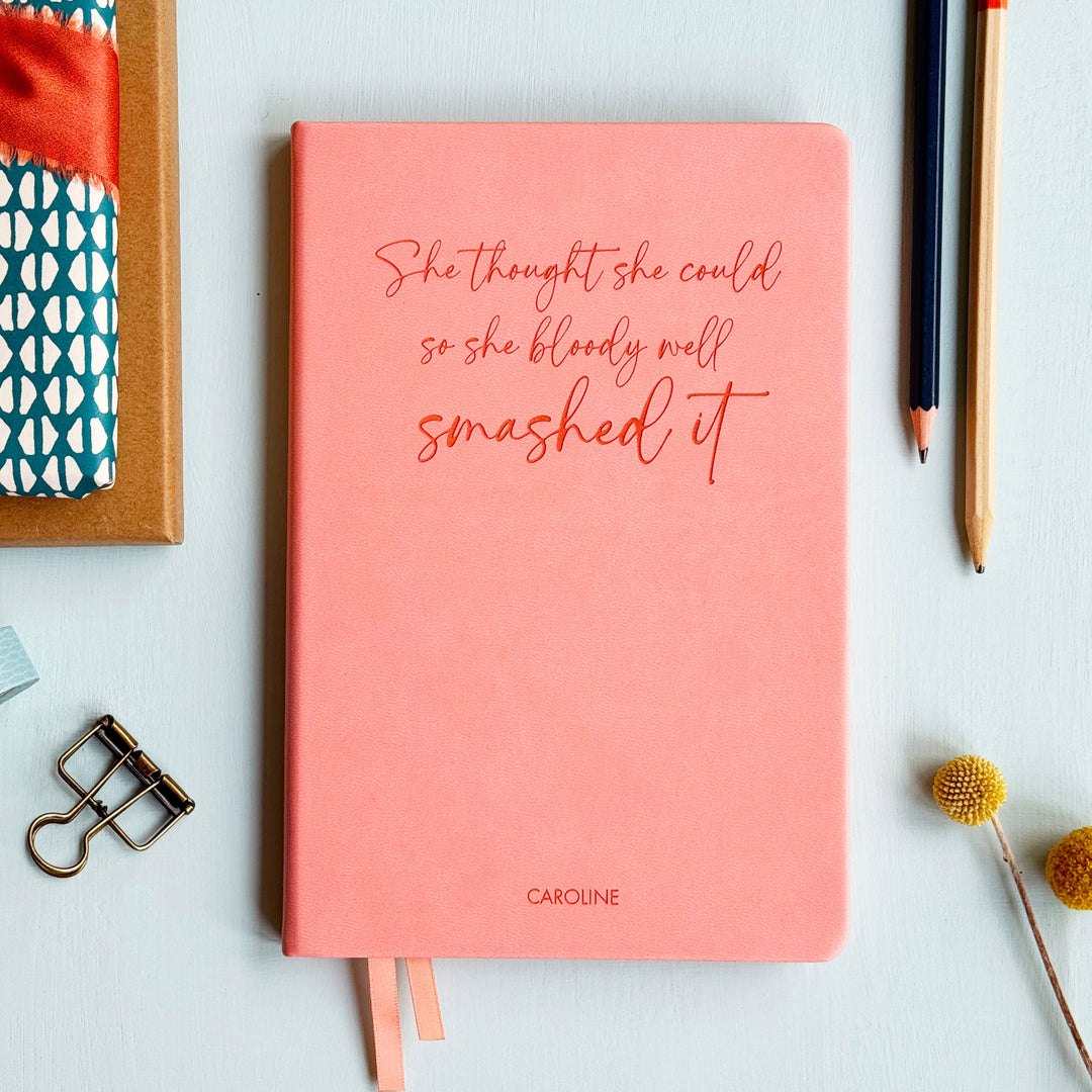 A5 lined pink notebook with 'She thought she could so she bloody well smashed it'  engraved on with the name Caroline small at the bottom.