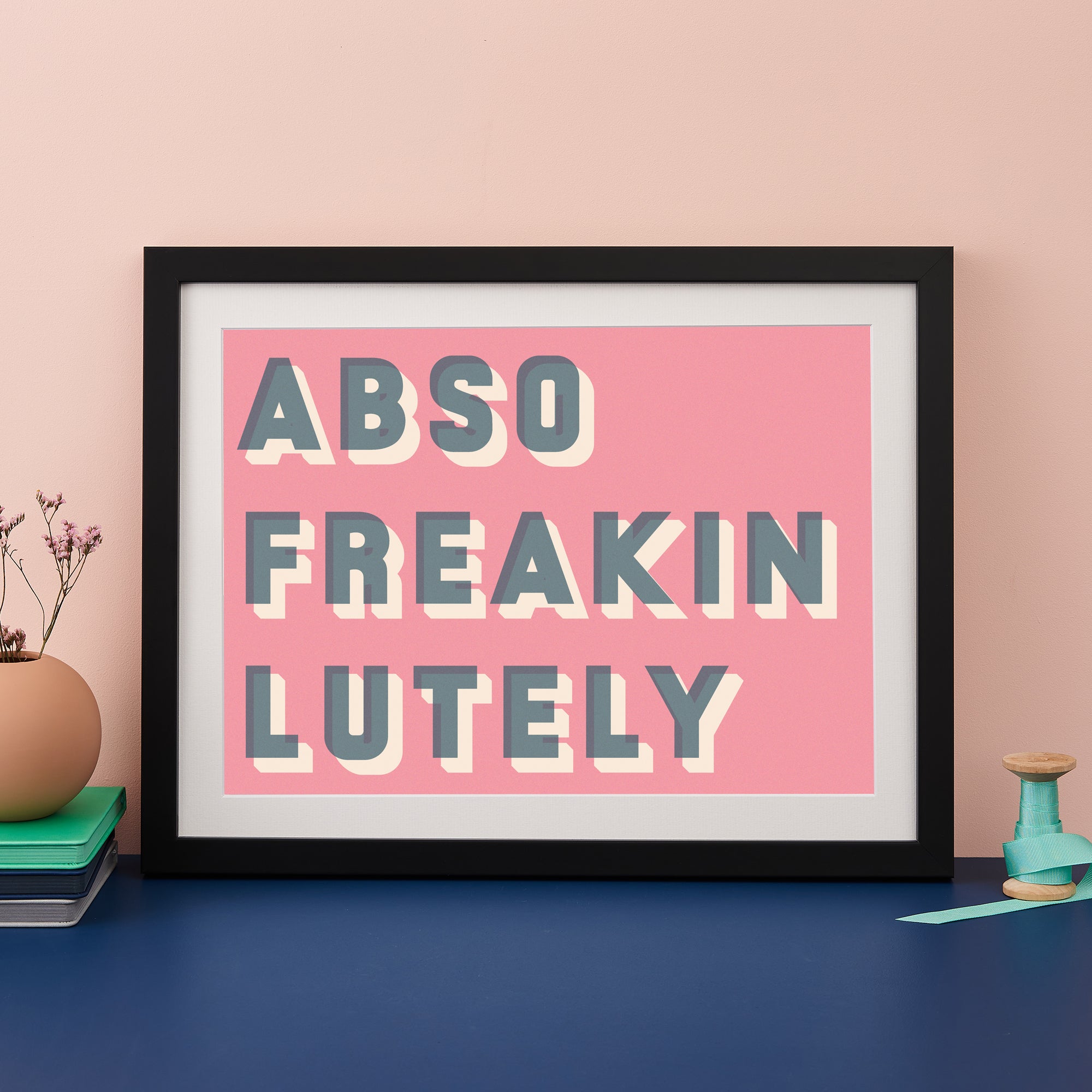 Black framed typographic print saying Abso Freakin Lutely on a pink background