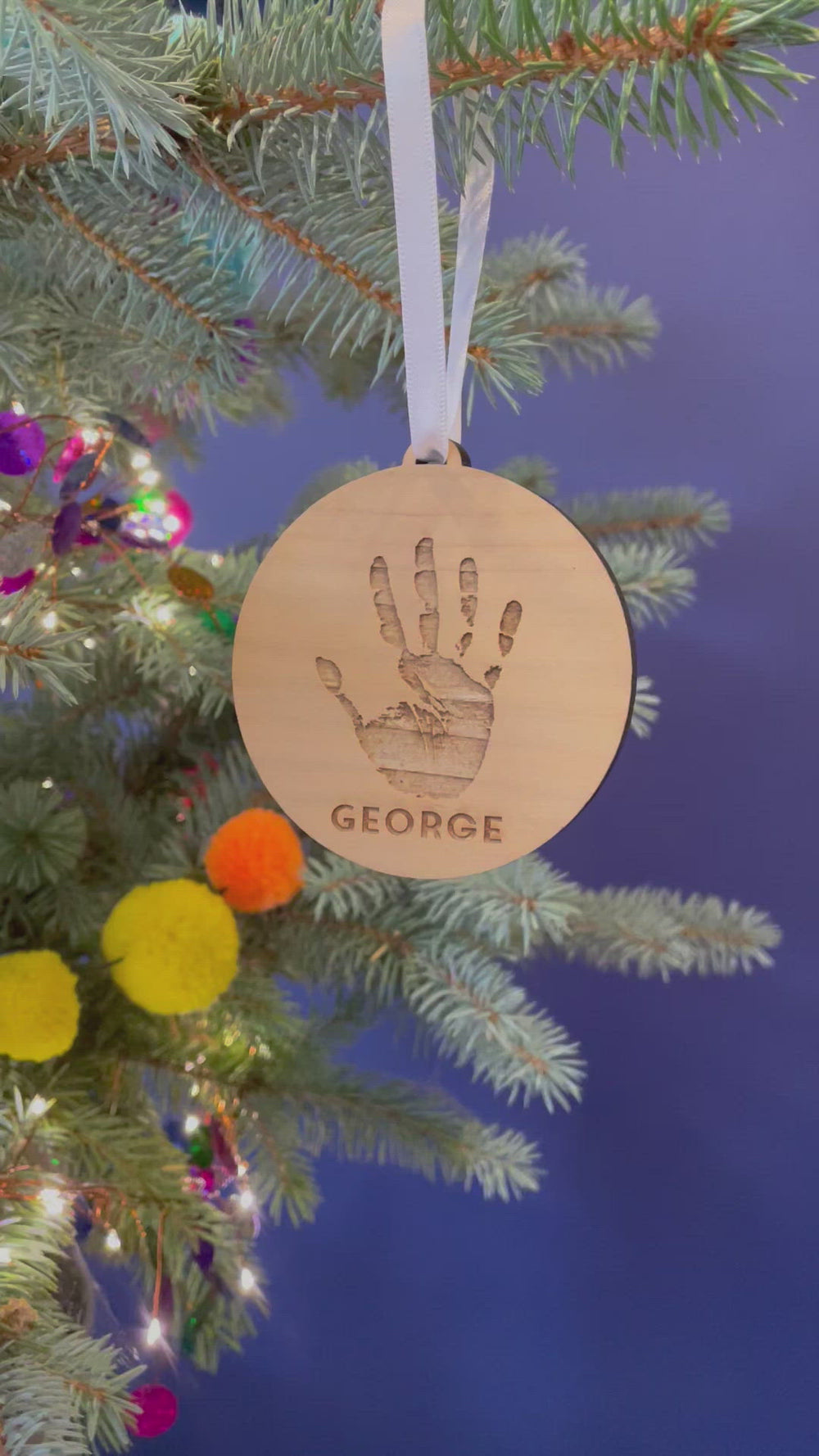 A video showing the decoration from different angles, hanging from a Christmas tree by a white satin ribbon.
