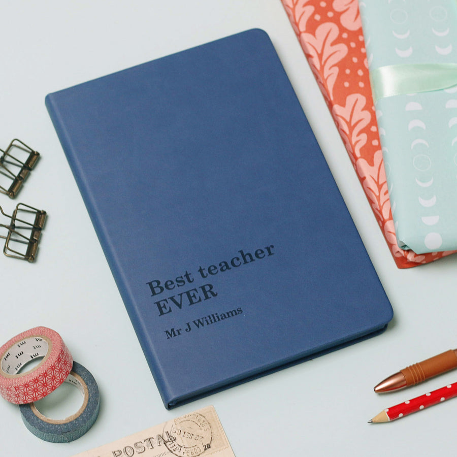 Blue notebook with 'Best teacher EVER' text on a light gray background