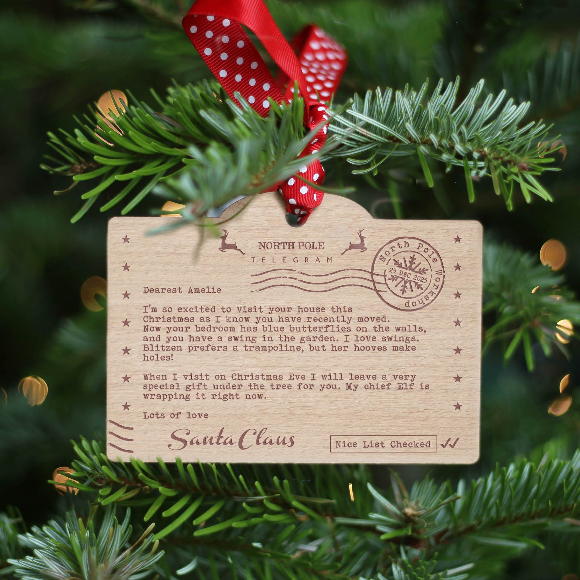 Santa's Nice list themed personalised wooden ornament with Santa Claus letter hung with red and white polka dot ribbon on a Christmas tree.