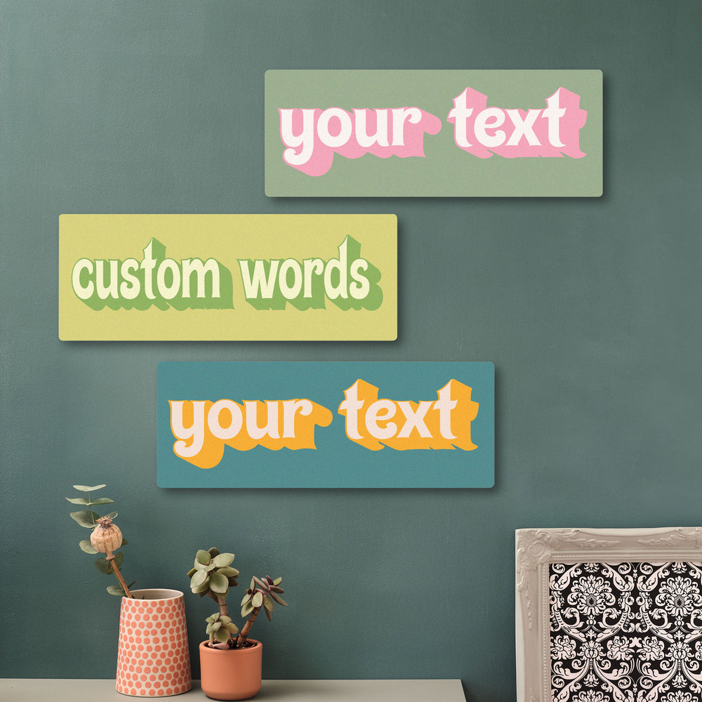 Three customizable text signs on a wall with decorative elements. These wooden wall art signs feature a great retro font and fabulous colours.