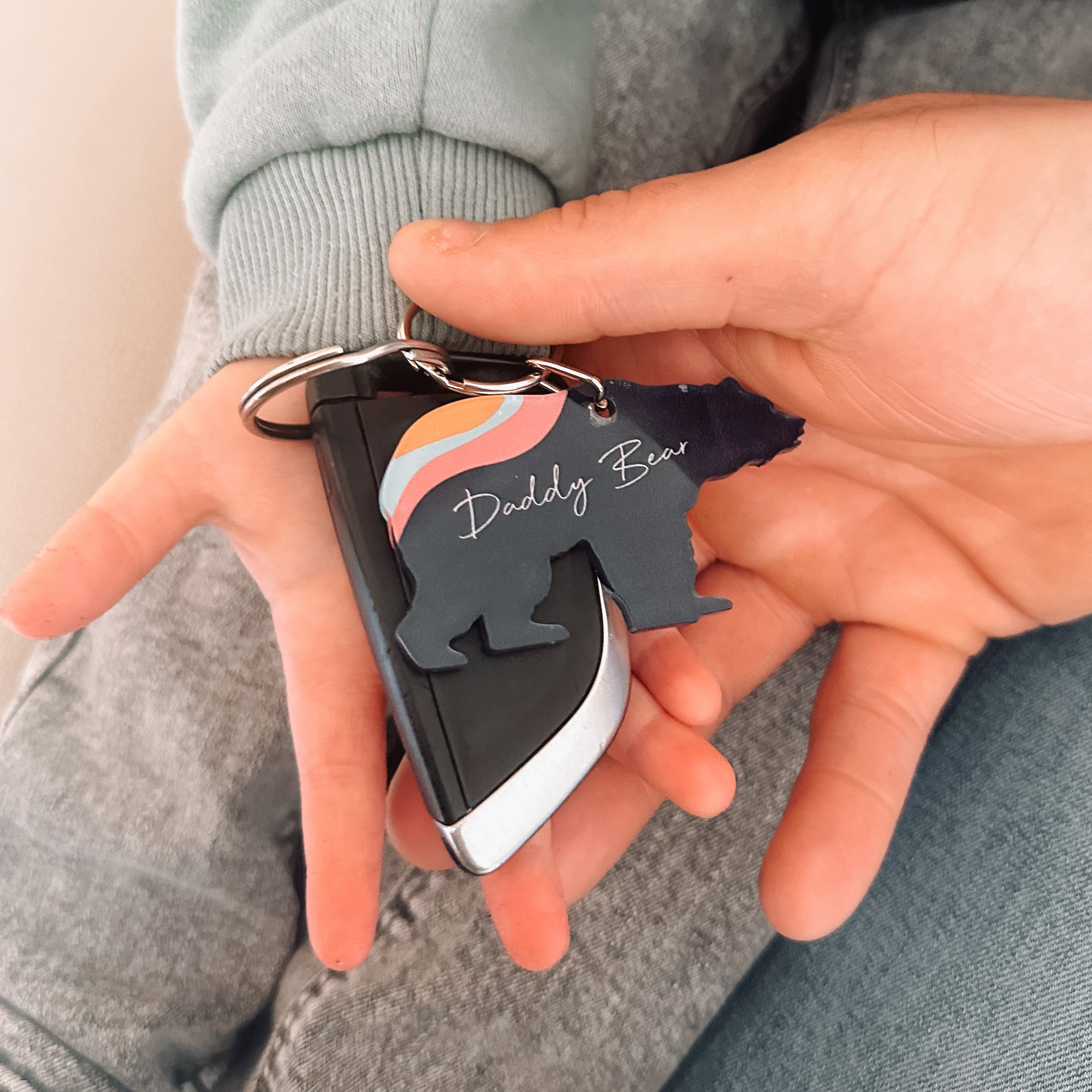 Father and child holding an acrylic aurora bear keyring attached to car key, perfect for new dads.