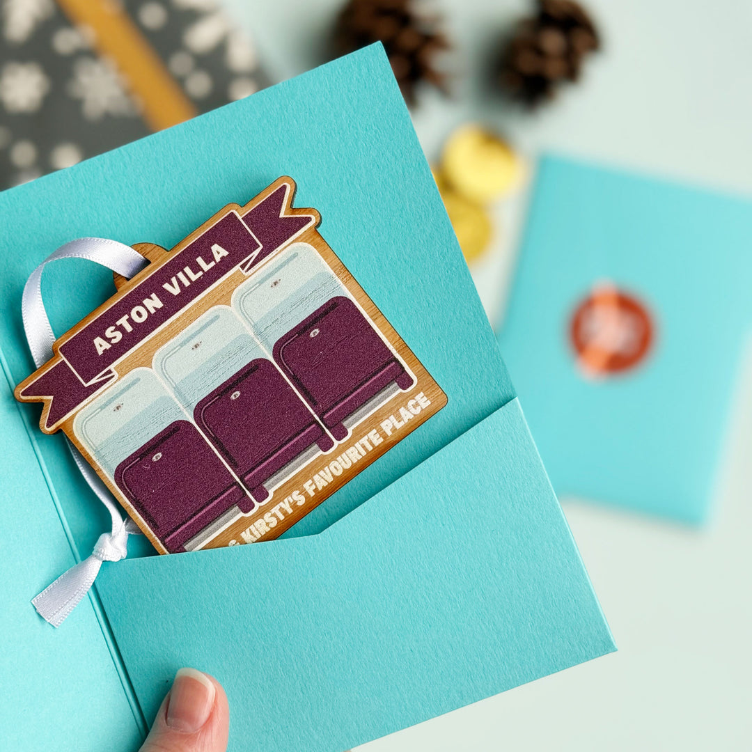 Sports-themed Christmas decoration with rugby or football stadium seating inside a blue gift sleeve.