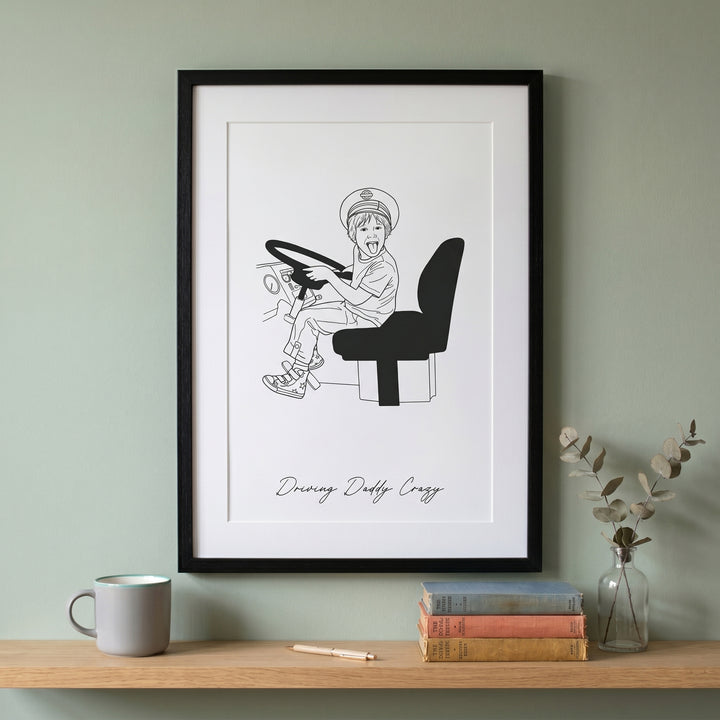 Framed black and white illustration of a child driving above a shelf with books and a mug.