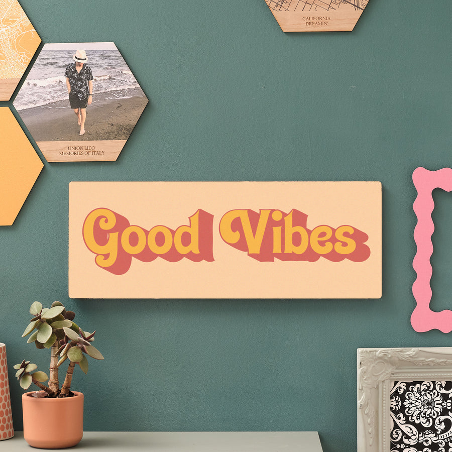 Good Vibes wooden wall art in beachy yellows displayed on a green wall with indoor plants and hexagon decor – perfect for uplifting hallway or home office styling.