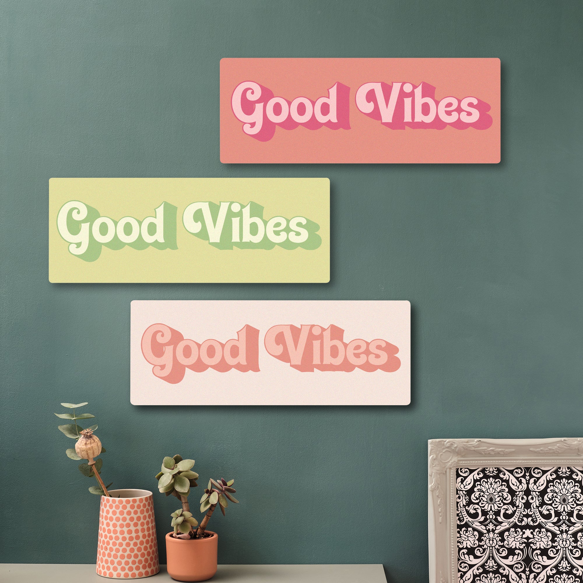 Feel-good wooden quote sign in a contemporary home setting, featuring Good Vibes message in pinks and greens on a green feature wall.