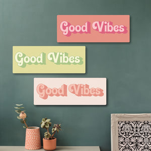 Feel-good wooden quote sign in a contemporary home setting, featuring Good Vibes message in pinks and greens on a green feature wall.