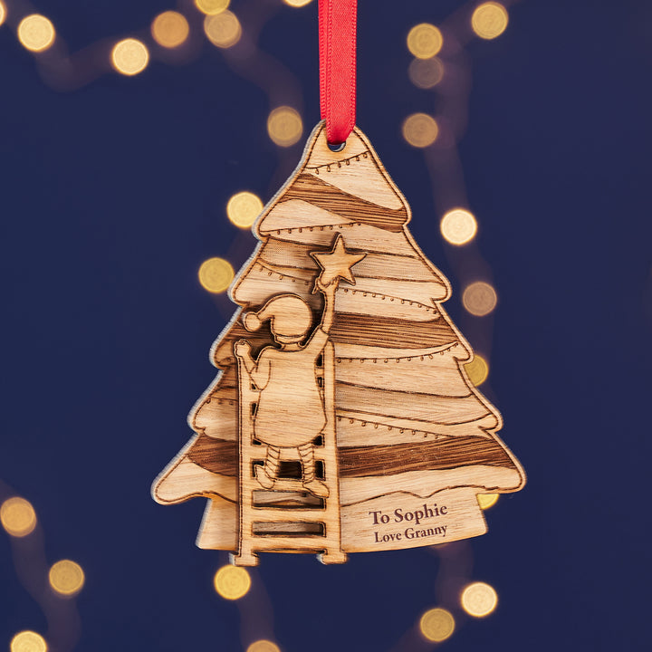 Wooden Christmas tree ornament with a child climbing to a star, on a dark blue background with lights.