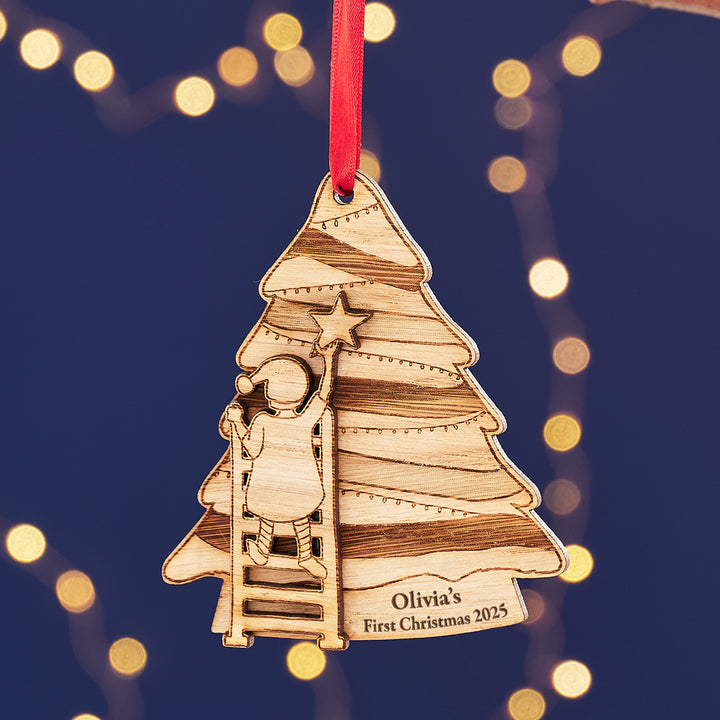 Personalised baby’s first Christmas ornament with a Christmas tree and a child carrying a star.