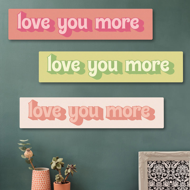 “Love You More” wooden wall art in pinks and greens  for long-distance relationships, shown in a cosy hallway setup