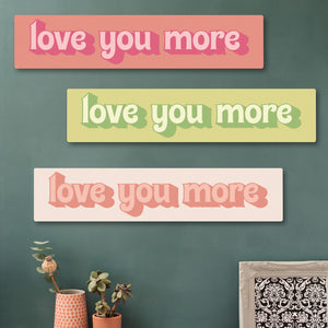 “Love You More” wooden wall art in pinks and greens  for long-distance relationships, shown in a cosy hallway setup