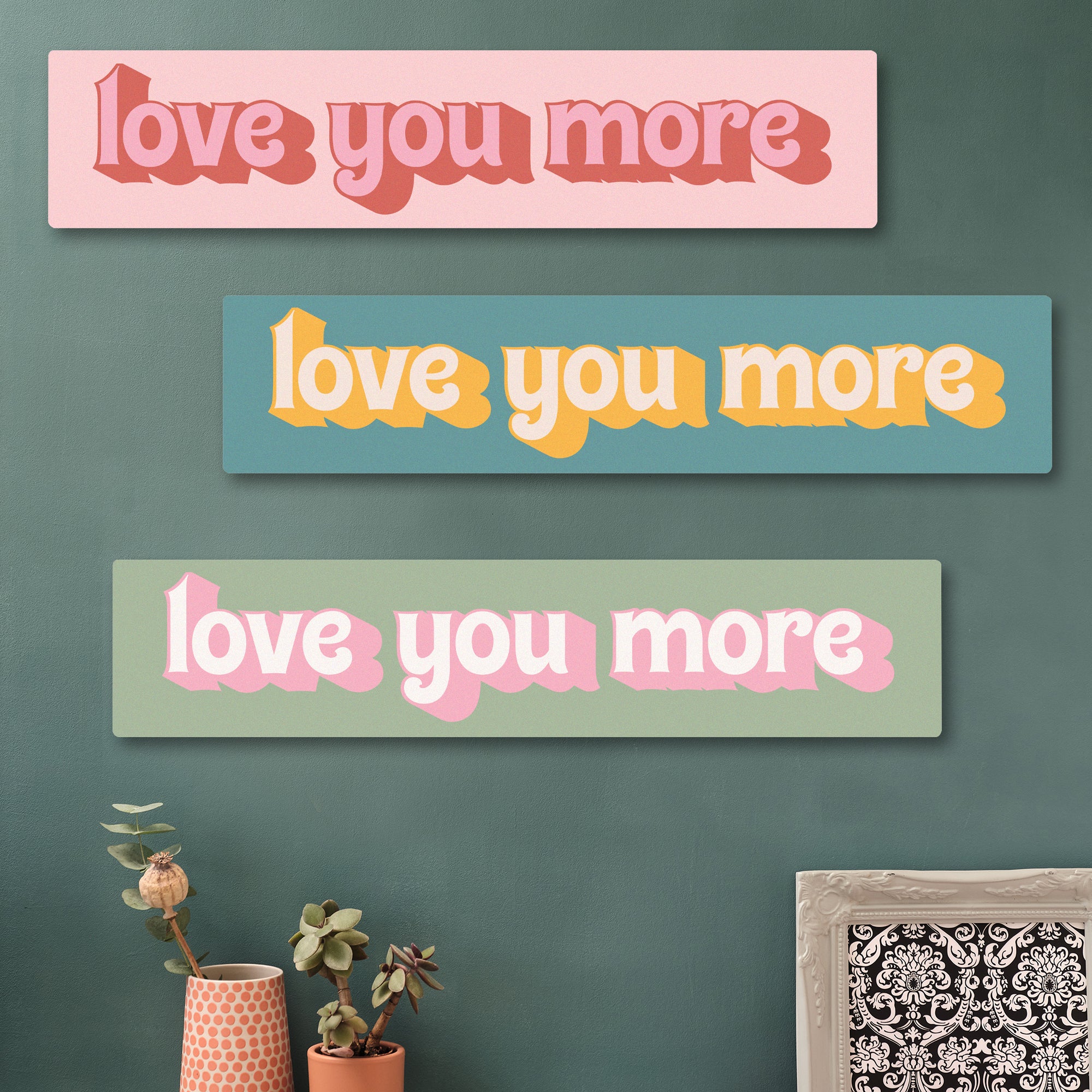 Wooden “Love You More” sign on green wall with gallery of hexagon art and plants – perfect hallway decor
