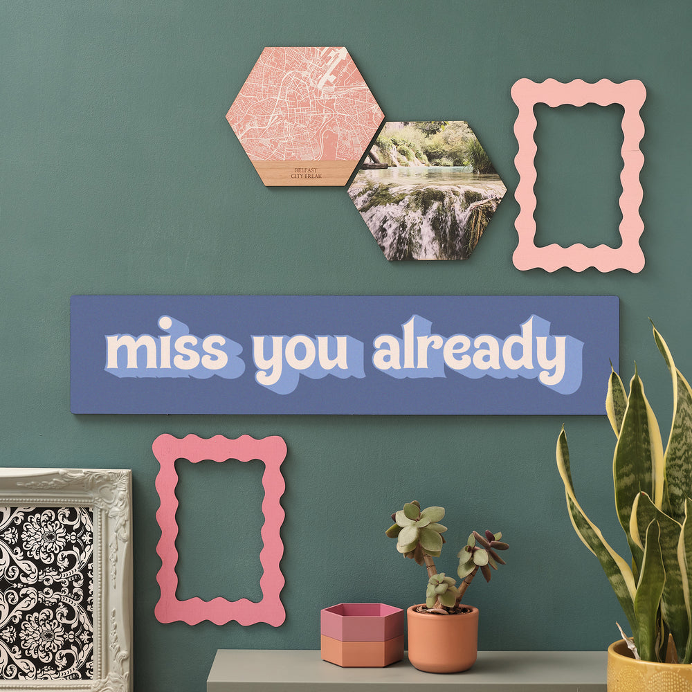 BLUE Wooden wall art sign reading “Miss You Already” styled on a green wall with indoor plants and hexagon tiles.