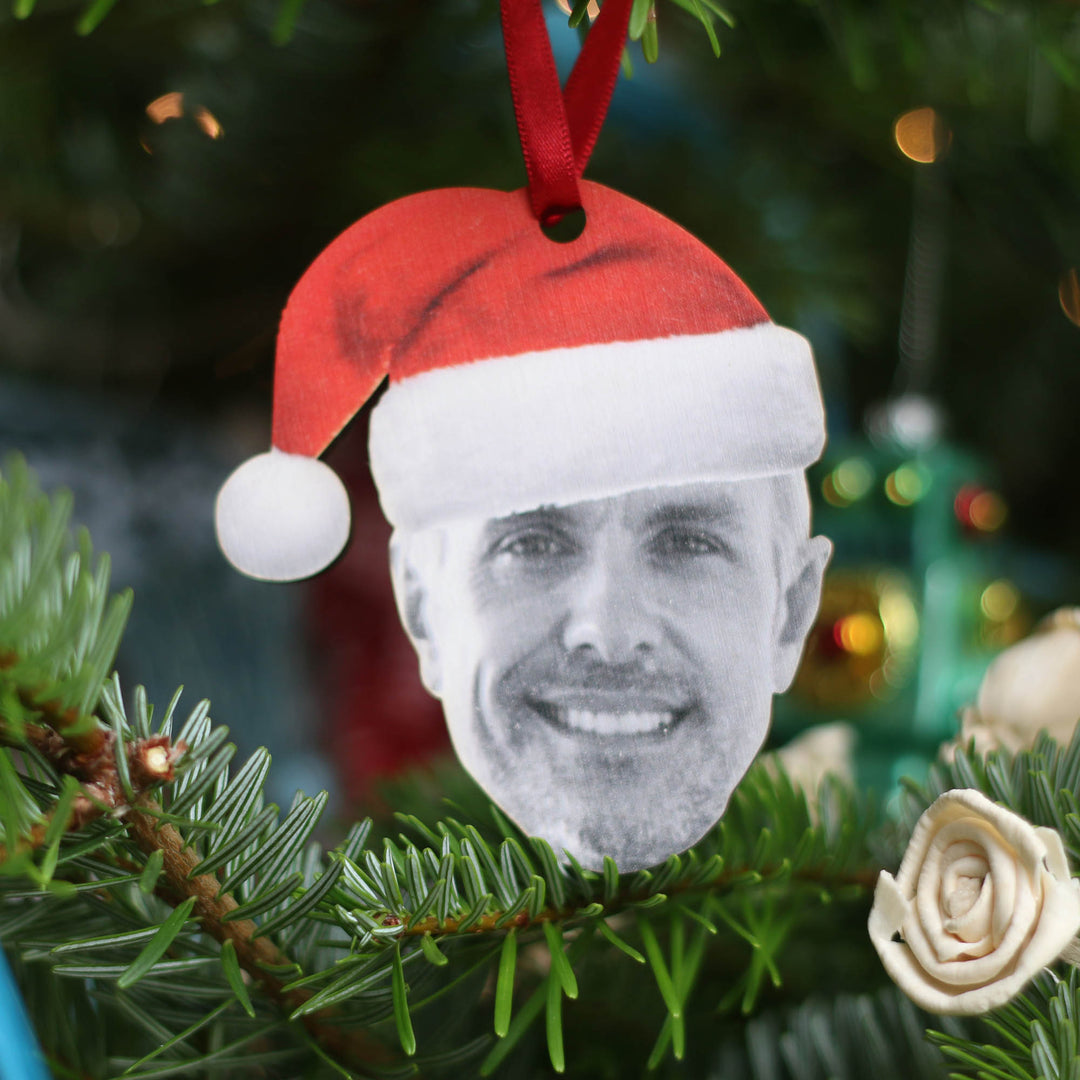 Rustic wooden bauble with an illustrated man wearing a red Santa hat.
