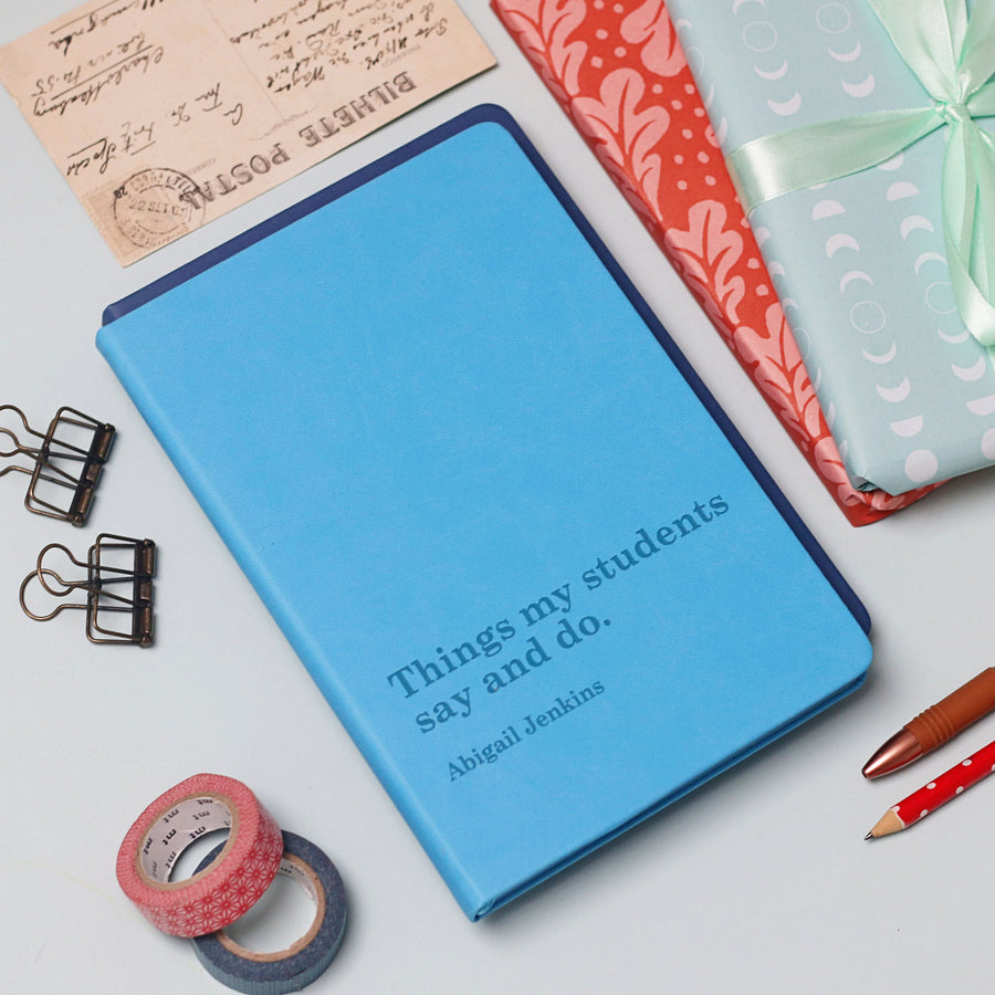 Blue notebook with text on a white surface with stationery items