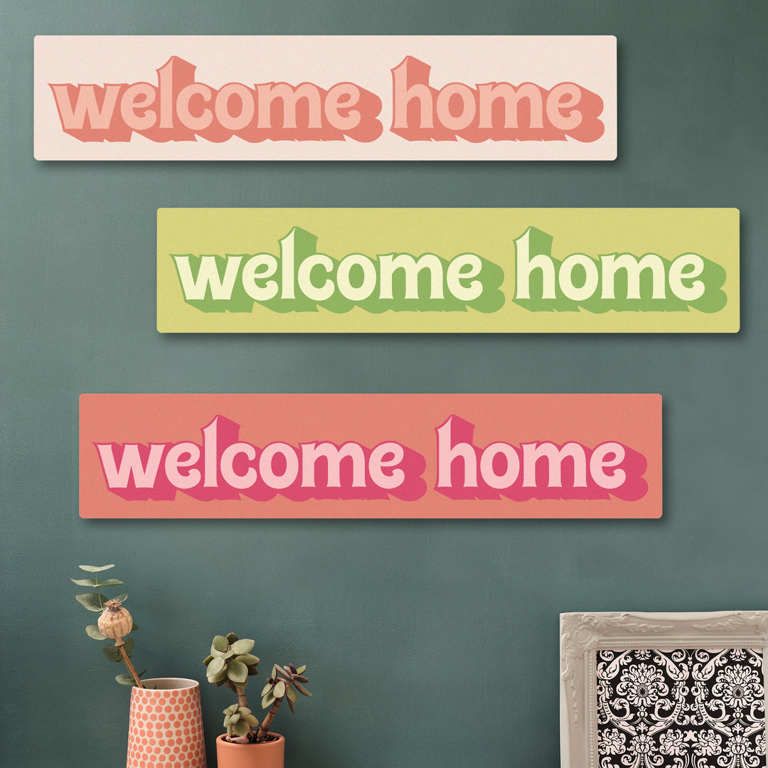 Colourful retro home decor sign that says “Welcome Home” in pinks and greens