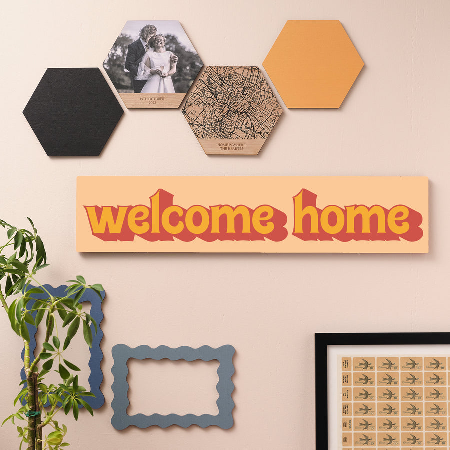 Welcome Home wooden wall sign in bold orange retro font styled on a green wall