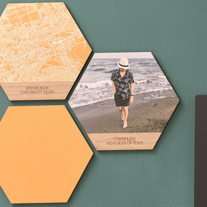 Three wooden hexagon picture tiles are mounted on a green wall. One shows a photo of a boy, one shows a solid yellow colour, and one shows a white map of Edinburgh on a yellow background.