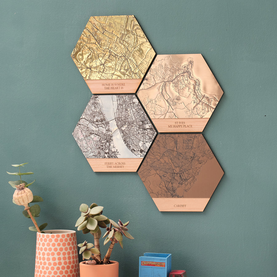 Stylish, unique and modern wall arts, a set of four metallic map hexagon tiles mounted on a wall, each with a different metallic finish and engraved with map locations for immortalising a special location such as a 'where we first met' gift or to commemorate a holiday or honeymoon.