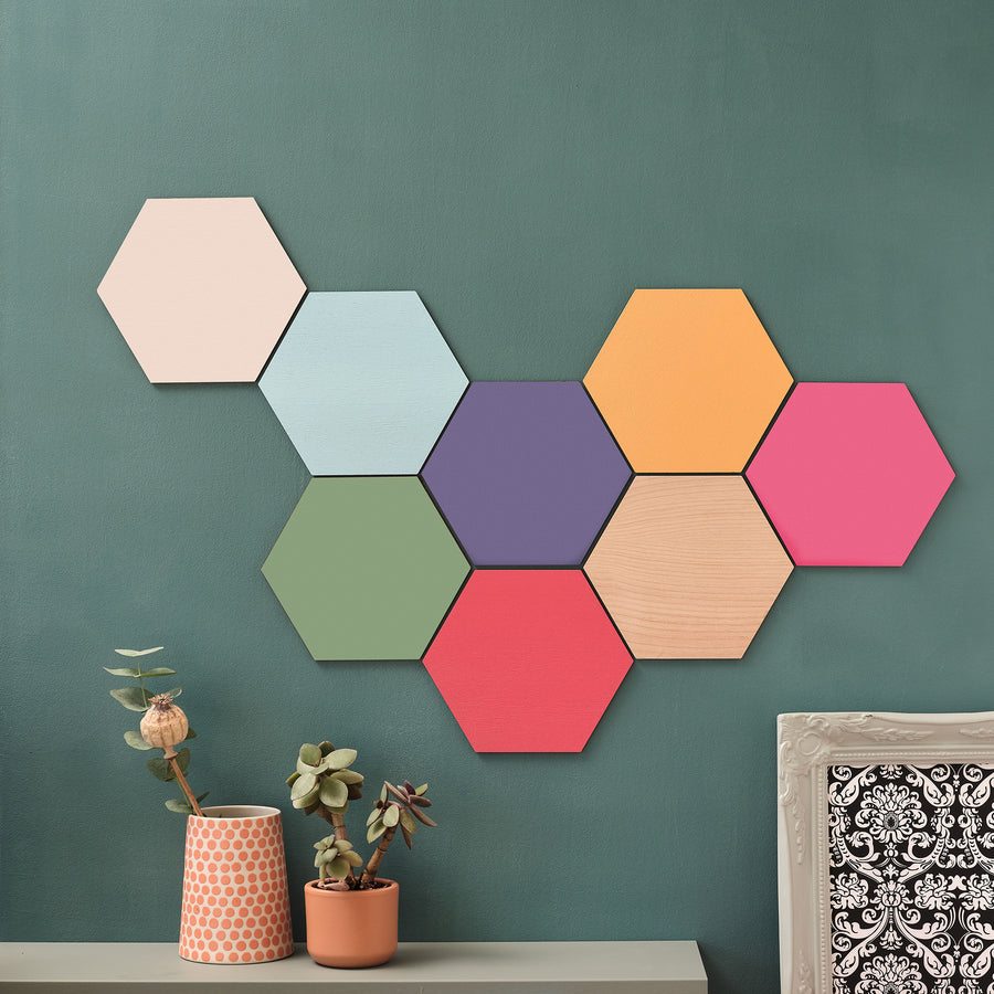 A wall adorned with a arrangement of plain and colourful wooden hexagon modern wall art print tiles in various shades, creating a geometric pattern.