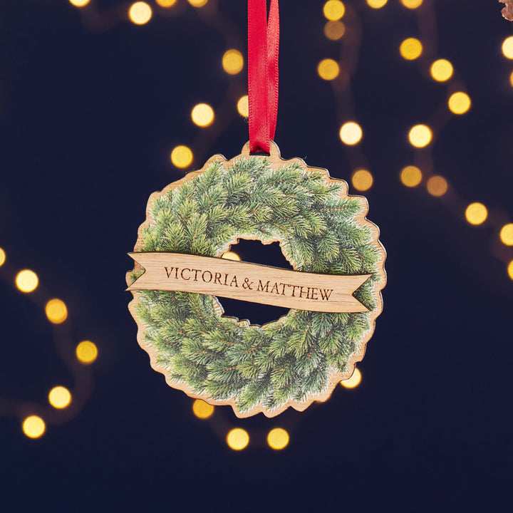 Personalised wooden wreath Christmas tree decoration with engraved family name on oak veneer.