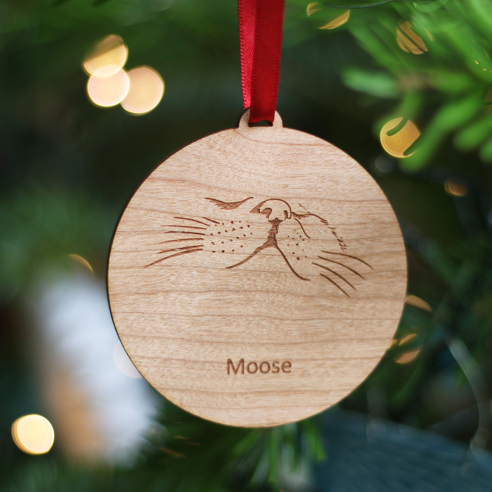 Eco-friendly wooden cat Christmas ornament with line drawing of cat’s nose and whiskers. Personalised with the cat's name and finished with a red satin ribbon.