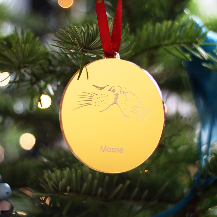 Personalised gold cat ornament for Christmas tree, minimalist nose design. Finished with a red satin ribbon and hanging on a fir tree.