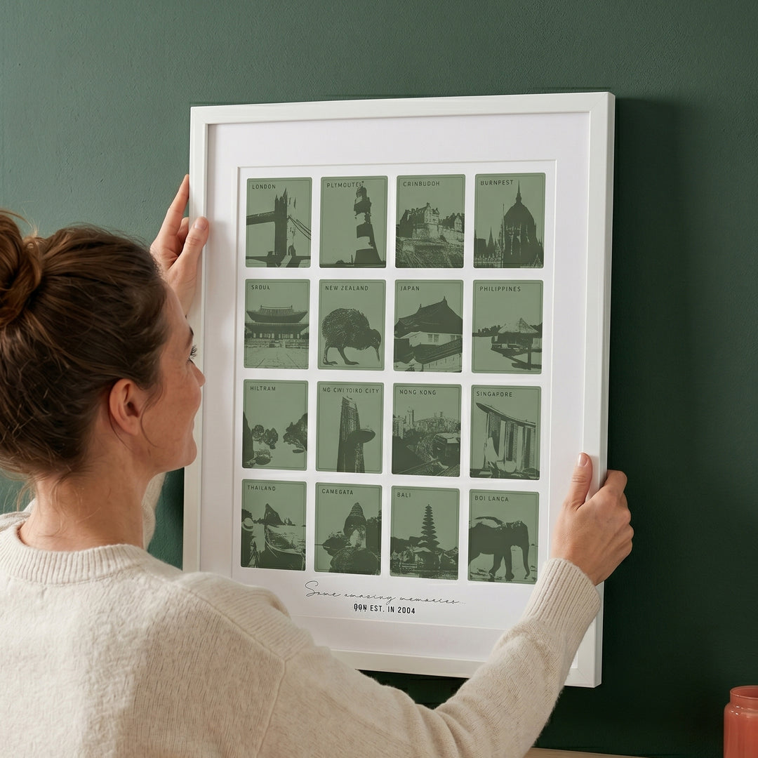 Person hanging a framed print with green travel memory images on a dark green wall
