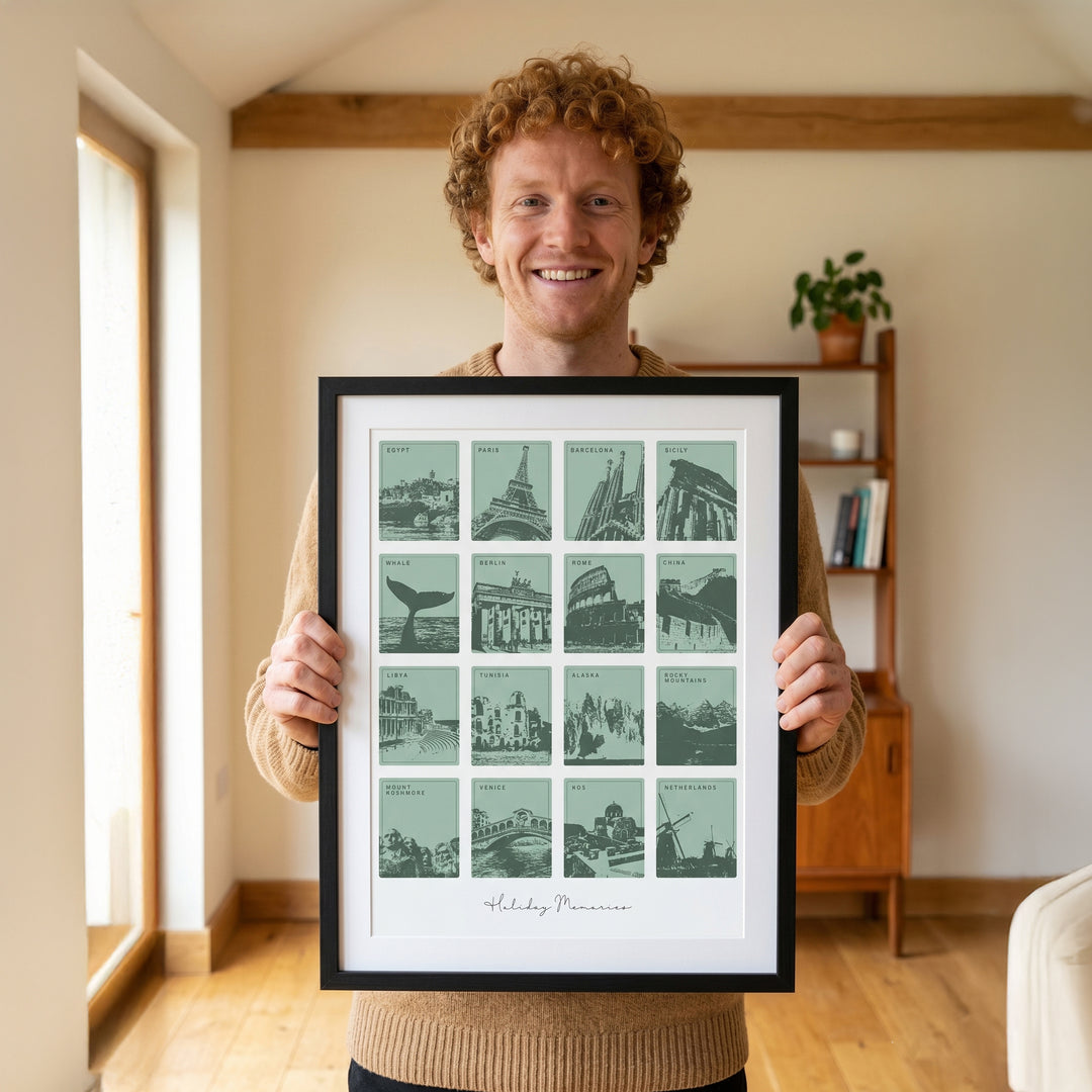 Man holding a framed print of cityscapes in a room with a bookshelf and plant.
