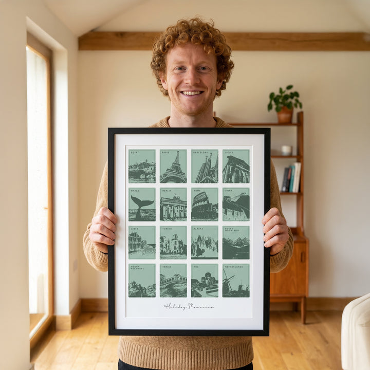 Man holding a framed print of cityscapes in a room with a bookshelf and plant.