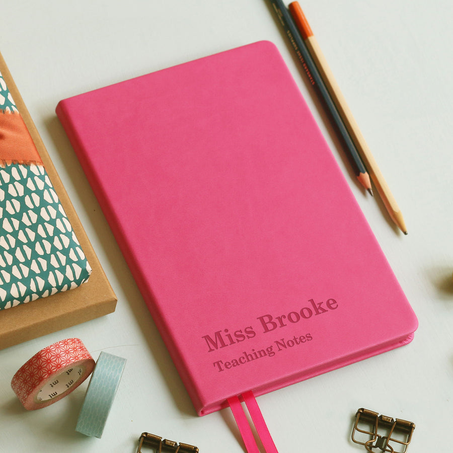 A vibrant notebook journal with engraved text with a teachers name followed by 'Teaching notes' on a modern background, perfect end of year gift for teachers.