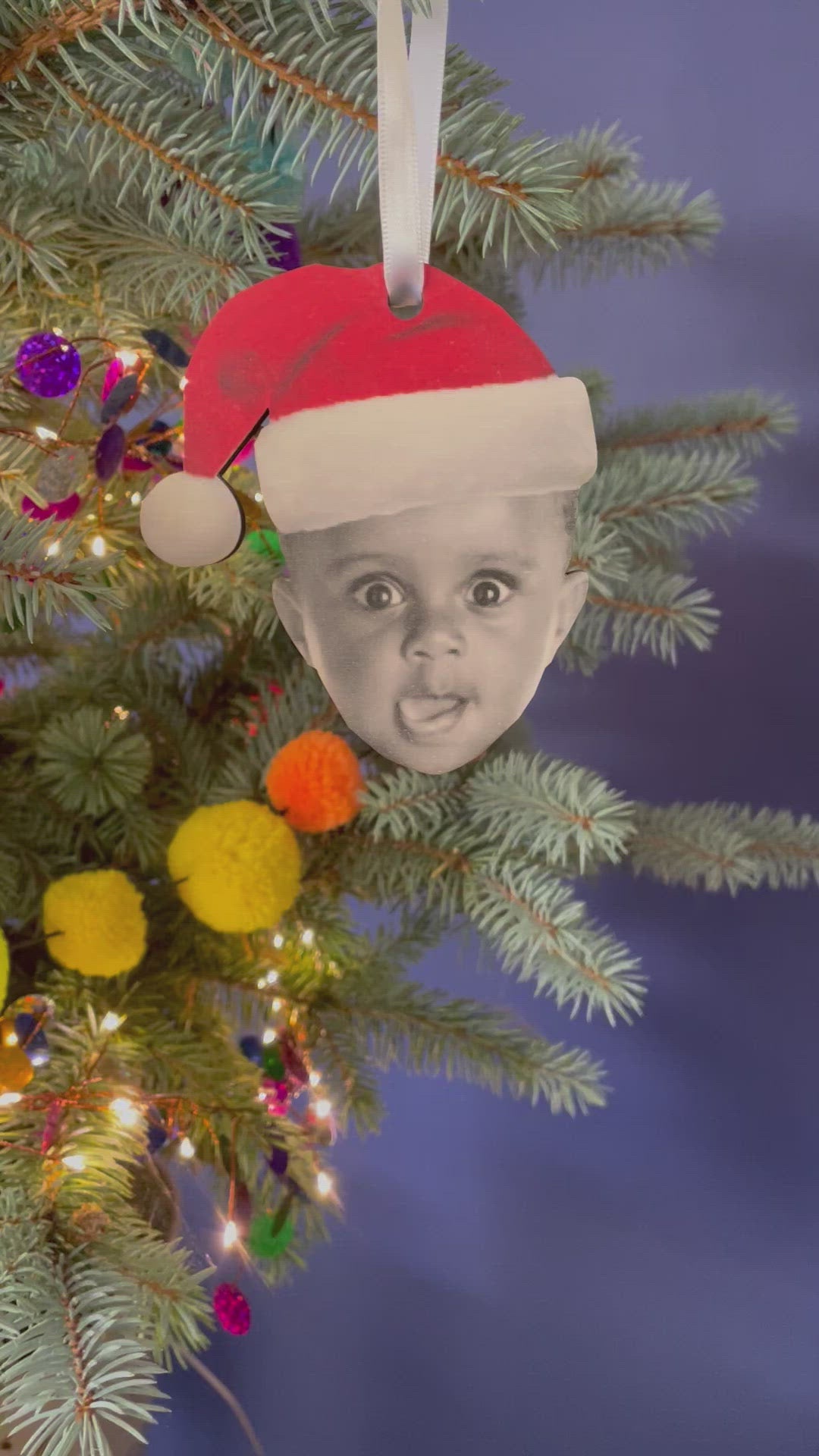 The video shows the decoration of the topper wearing a Santa hat from different angles on a Christmas tree.