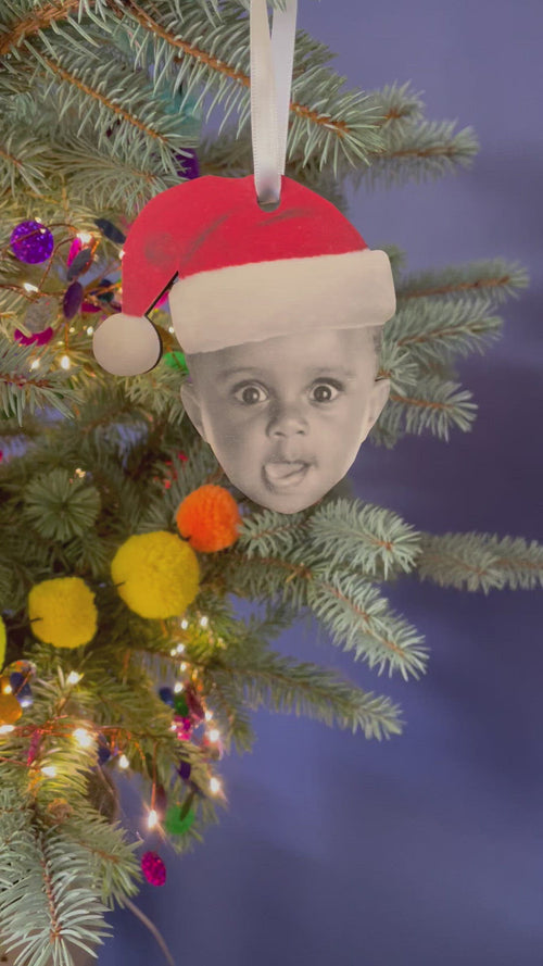 The video shows the decoration of the topper wearing a Santa hat from different angles on a Christmas tree.