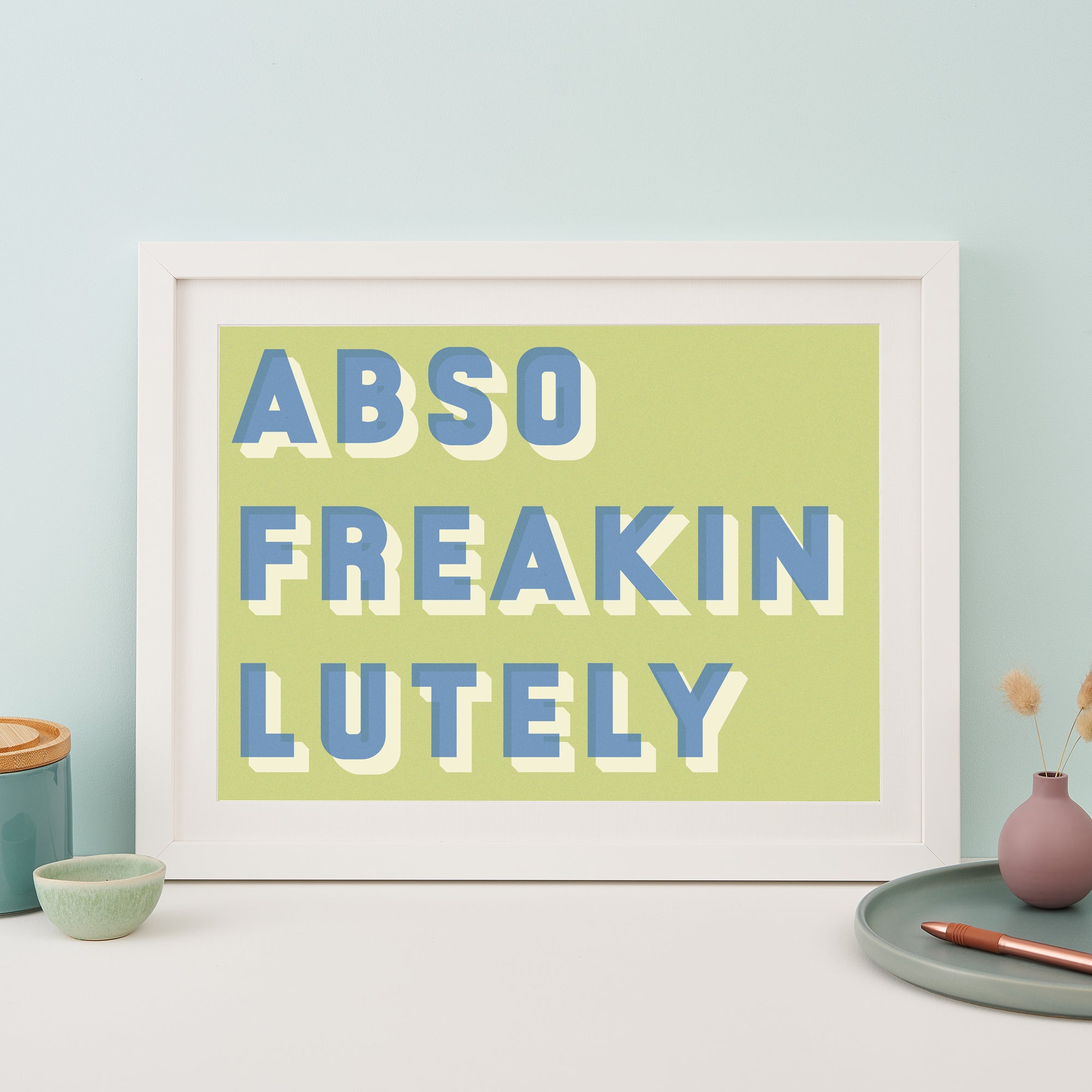 White framed typographic print saying Abso Freakin Lutely on a green background