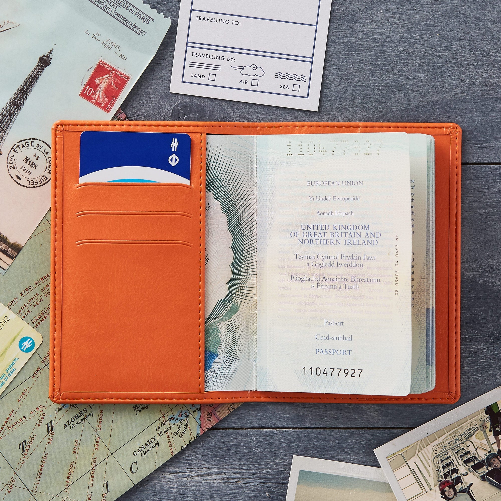 Passport holder lying flat open on table to show 3 card slots and the pocket holding a passport