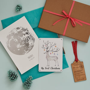 Letterbox gift with a silver moon personalised print, hand painted print of a reindeer and a luggage tag shaped wooden decoration engraved with a typed message from Father Christmas
