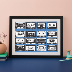 Framed print with 16 monochrome music cassettes on a blue background and personalised text.