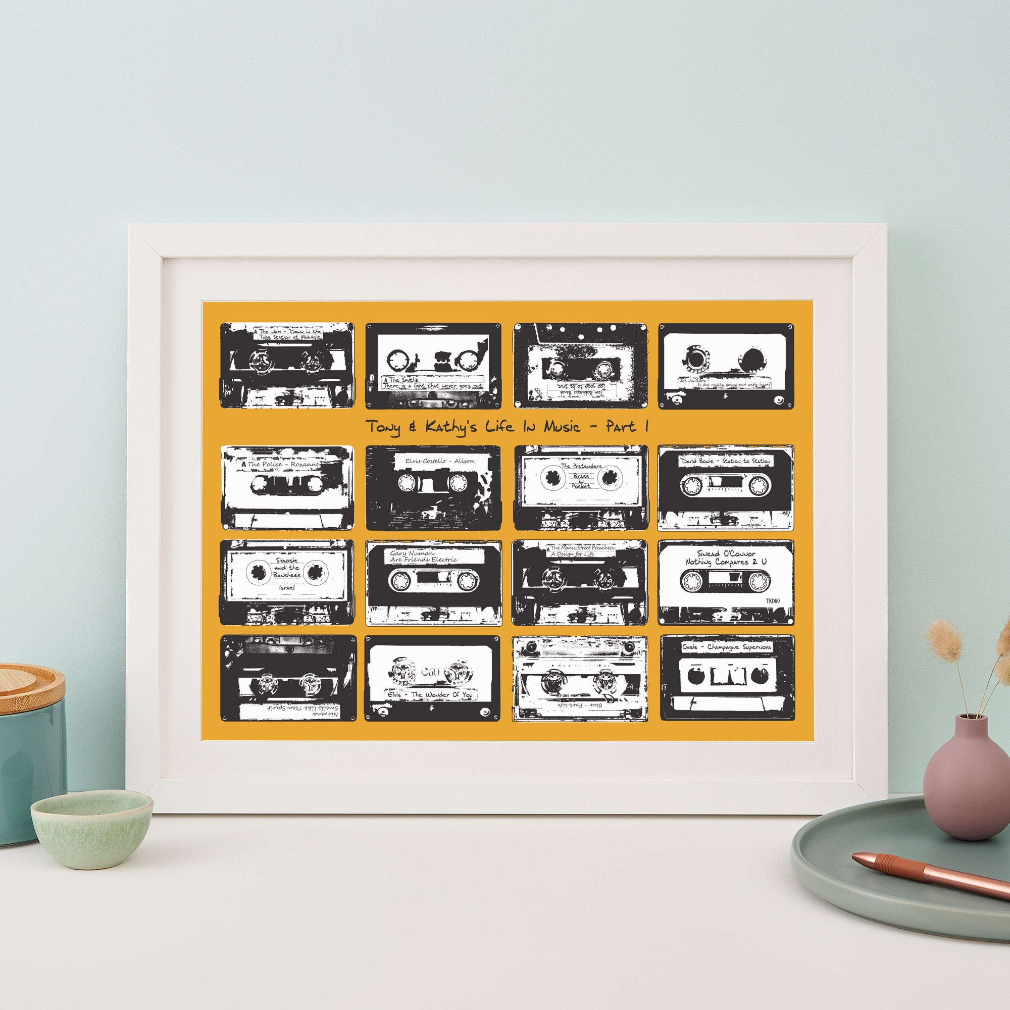 Framed print with 16 monochrome music cassettes on a gold coloured background and personalised text.