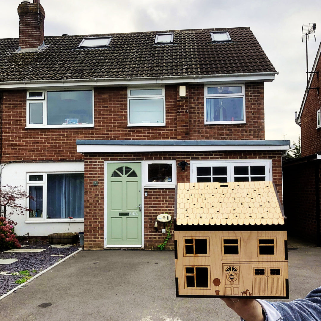Personalised Wooden Christmas Eve Box House, being held in front of the house it was made to look like.