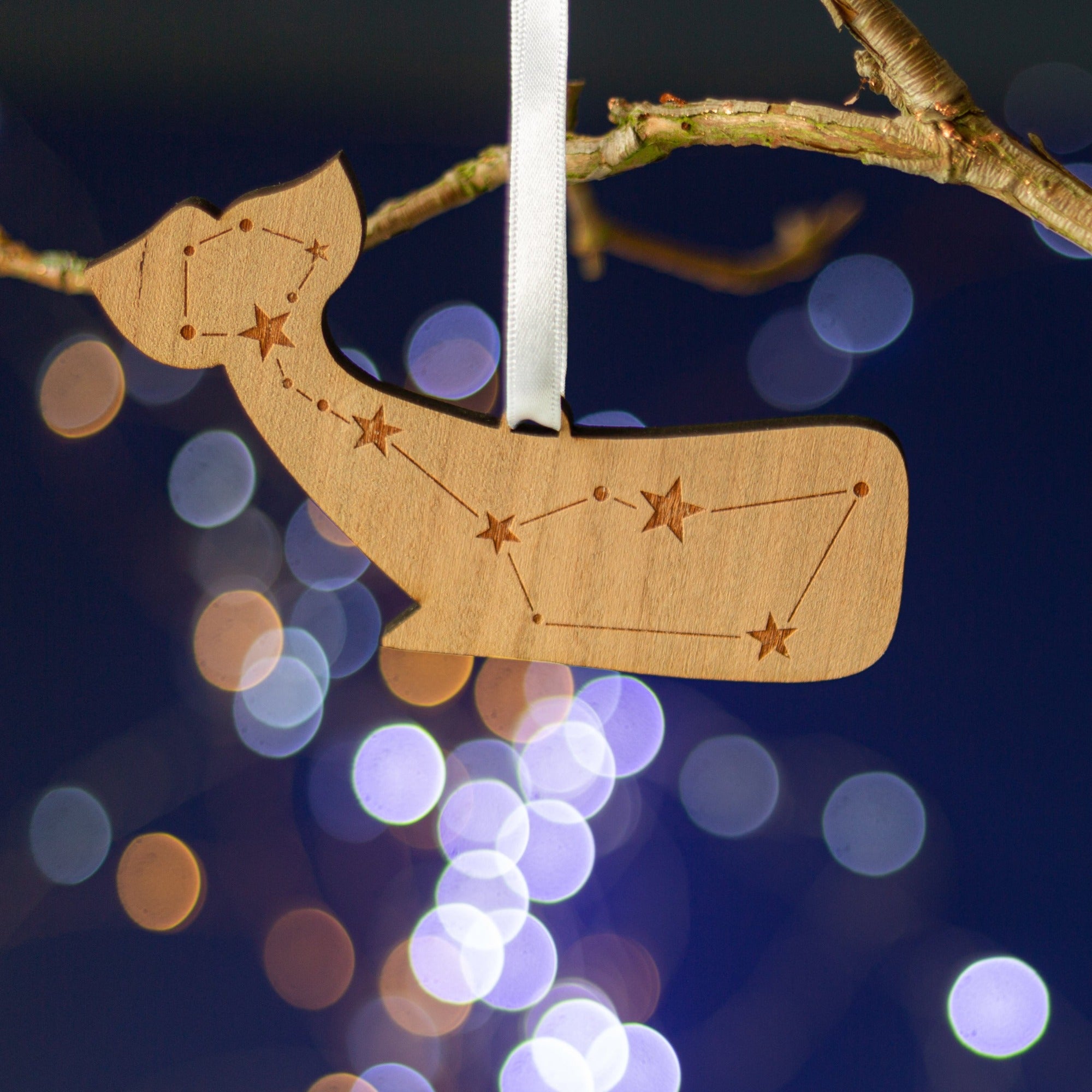 Wooden Christmas decoration in the shape of a while, with stars engraved on the front.