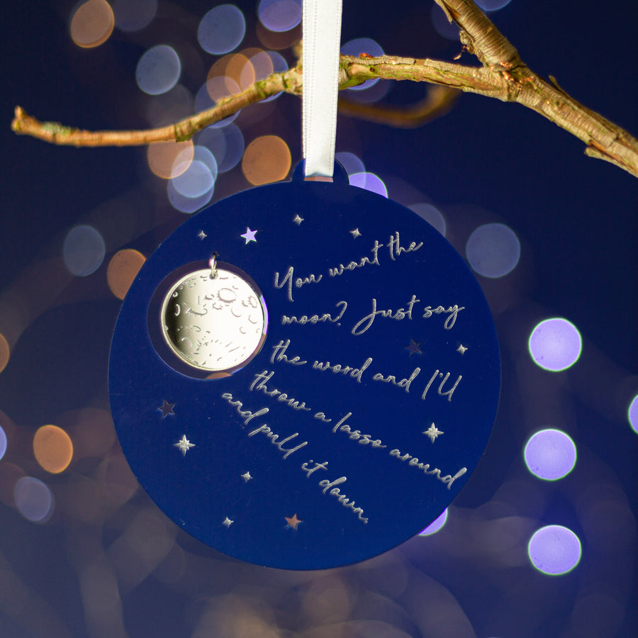 A blue Christmas tree decoration with a silver moon and a quote from the film 'It's A Wonderful Life'.