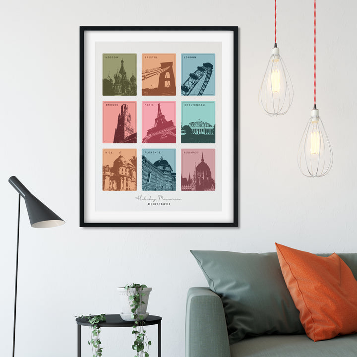framed print with nine colorful squares, each depicting a different European city landmark, hangs above a gray couch with orange pillows. The print is personalized with "Holiday Memories" and "All Our Travels." Two pendant lights hang above the couch.
