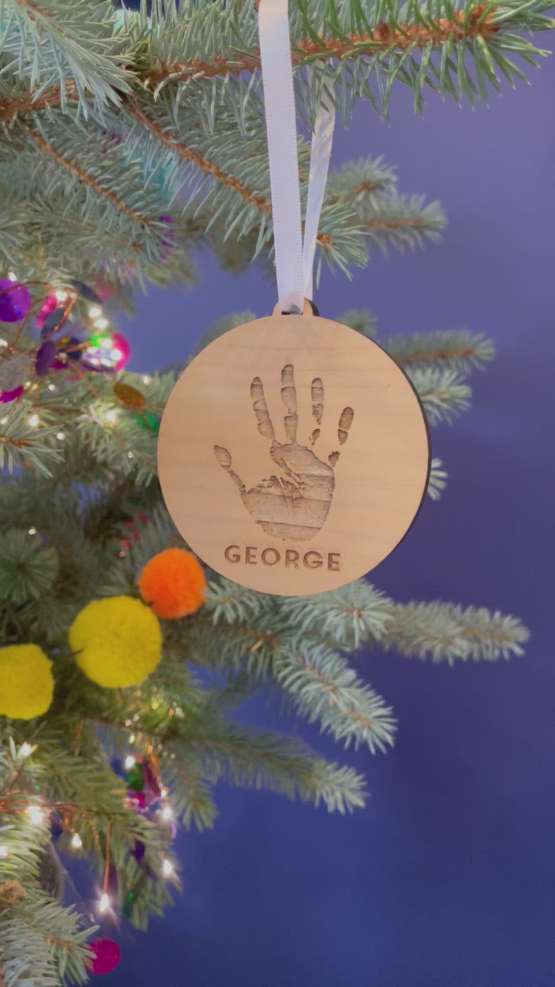 A video showing the decoration from different angles, hanging from a Christmas tree by a white satin ribbon.